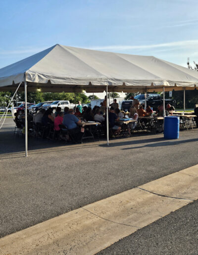 People enjoying the outdoor setting under the tent at the crab feast